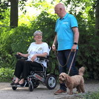 Feedbeck Bild Frau mit Rollstuhl und Mann mit Hund im Park