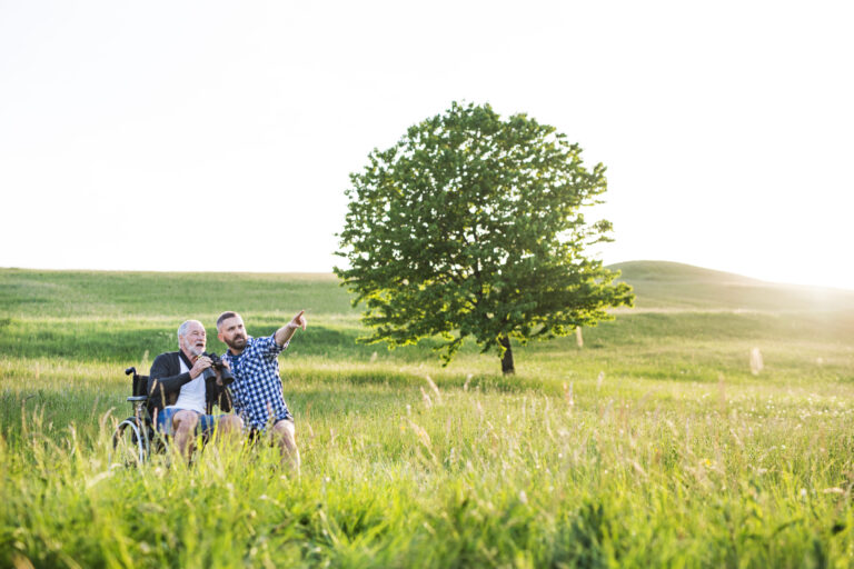 Mann im Rollstuhl mit seinem Sohn auf einem Feld - GPS-Tracker f&uuml;r Demenzerkrankte