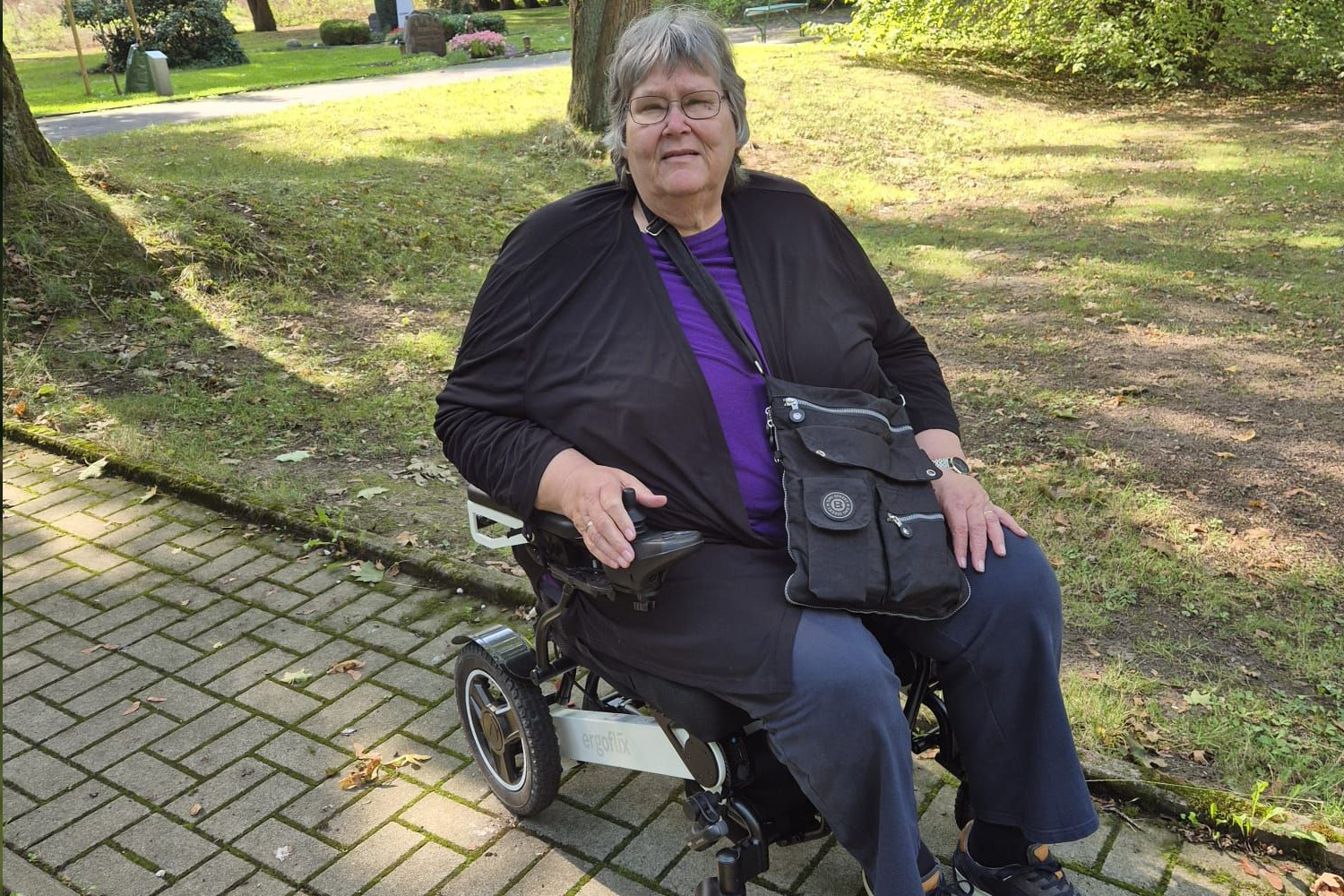 Das Bild zeigt eine Frau, die in einem ergoflix® LX sitzt und sich neben einer Wiese befindet.