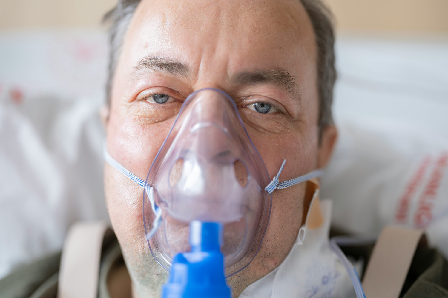 Das Bild zeigt das Gesicht eines Mannes, der über eine Maske an ein Sauerstoffgerät angeschlossen ist.