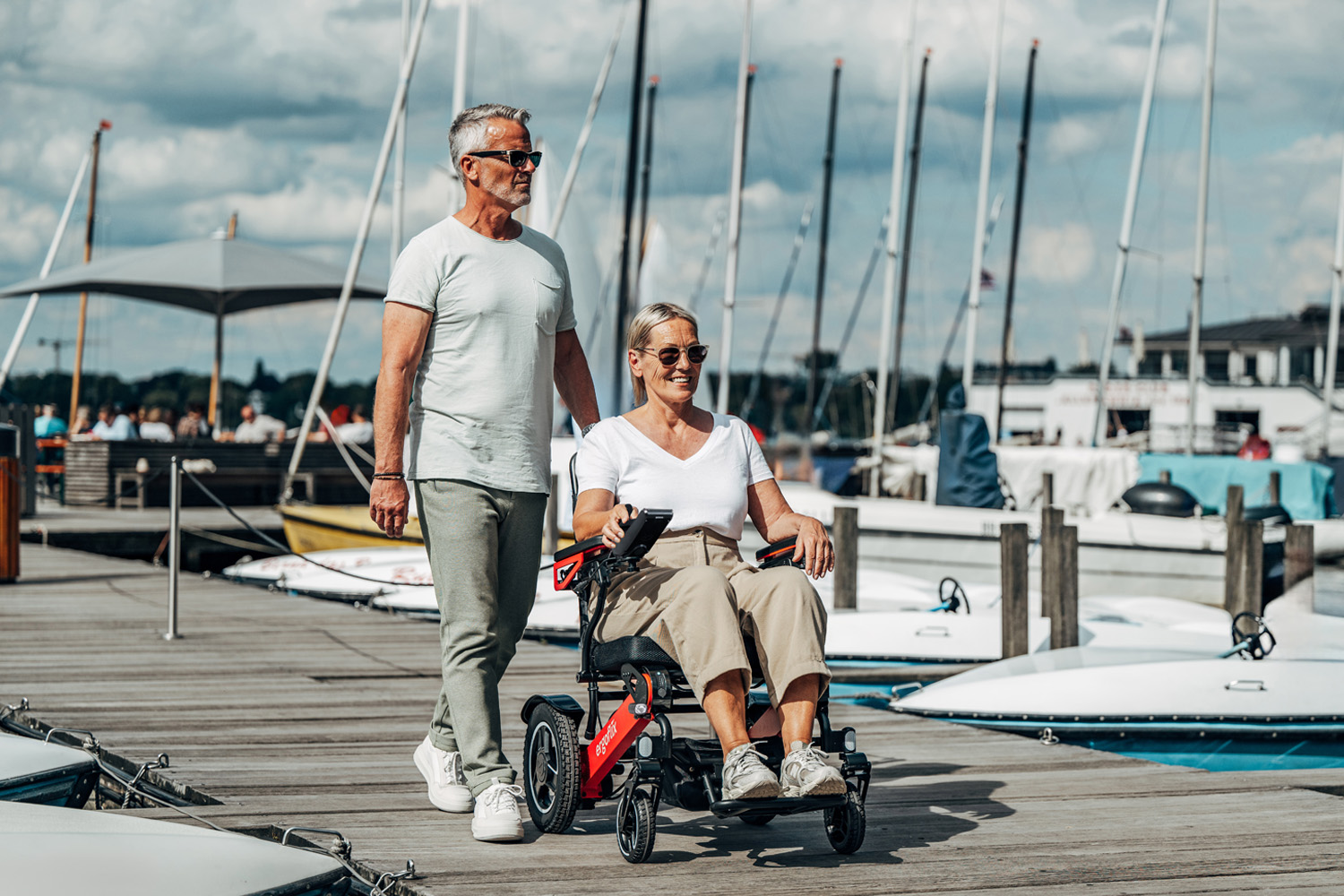 Das Bild zeigt eine Frau in einem ergoflix LX, ein Mann läuft neben ihr und beide befinden sich auf einem Steg am Hafen.