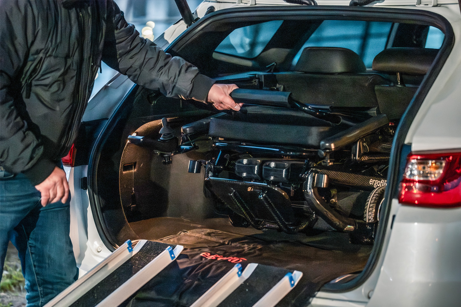 Das Foto zeigt einen Rollstuhl, der zusammengefaltet im Kofferraum eines Autos liegt.