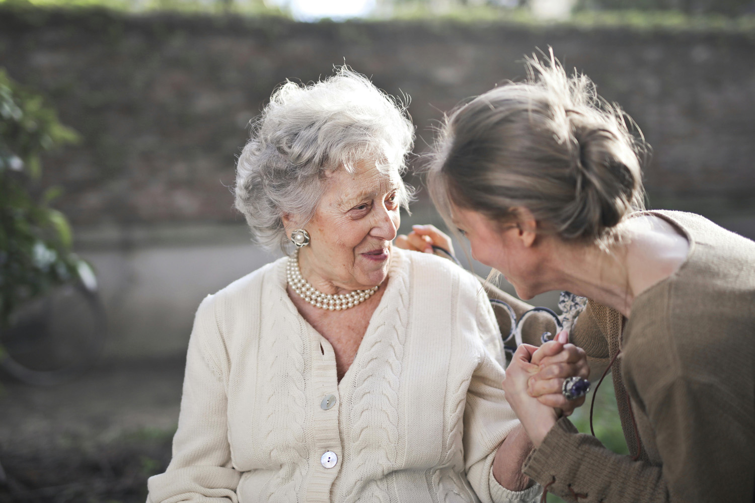 Das Bild zeigt eine ältere Frau, die sich gerade im Gespräch mit einer jüngeren Frau befindet.