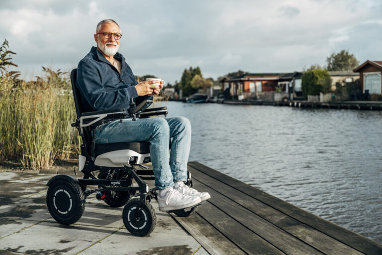 Das Bild zeigt einen Mann im ergoflix vario, der sich am Ufer eines Gew&auml;ssers befindet und eine Tasse Kaffee in der Hand h&auml;lt.