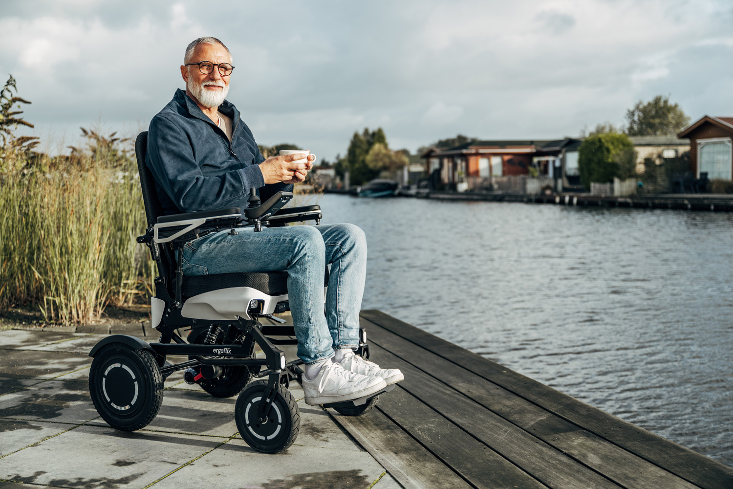 Das Bild zeigt einen Mann im ergoflix vario, der sich am Ufer eines Gewässers befindet und eine Tasse Kaffee in der Hand hält.