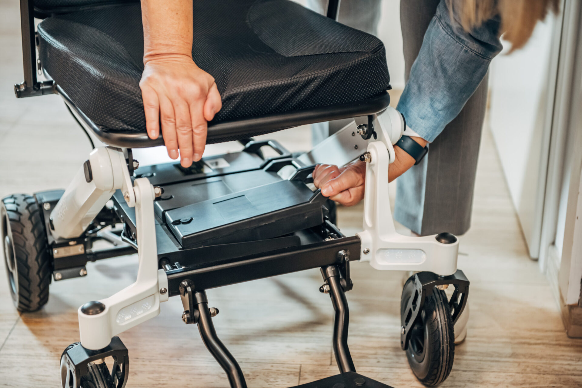 Dieses Bild zeigt eine Dame, die einen Rollstuhlakku entnimmt.