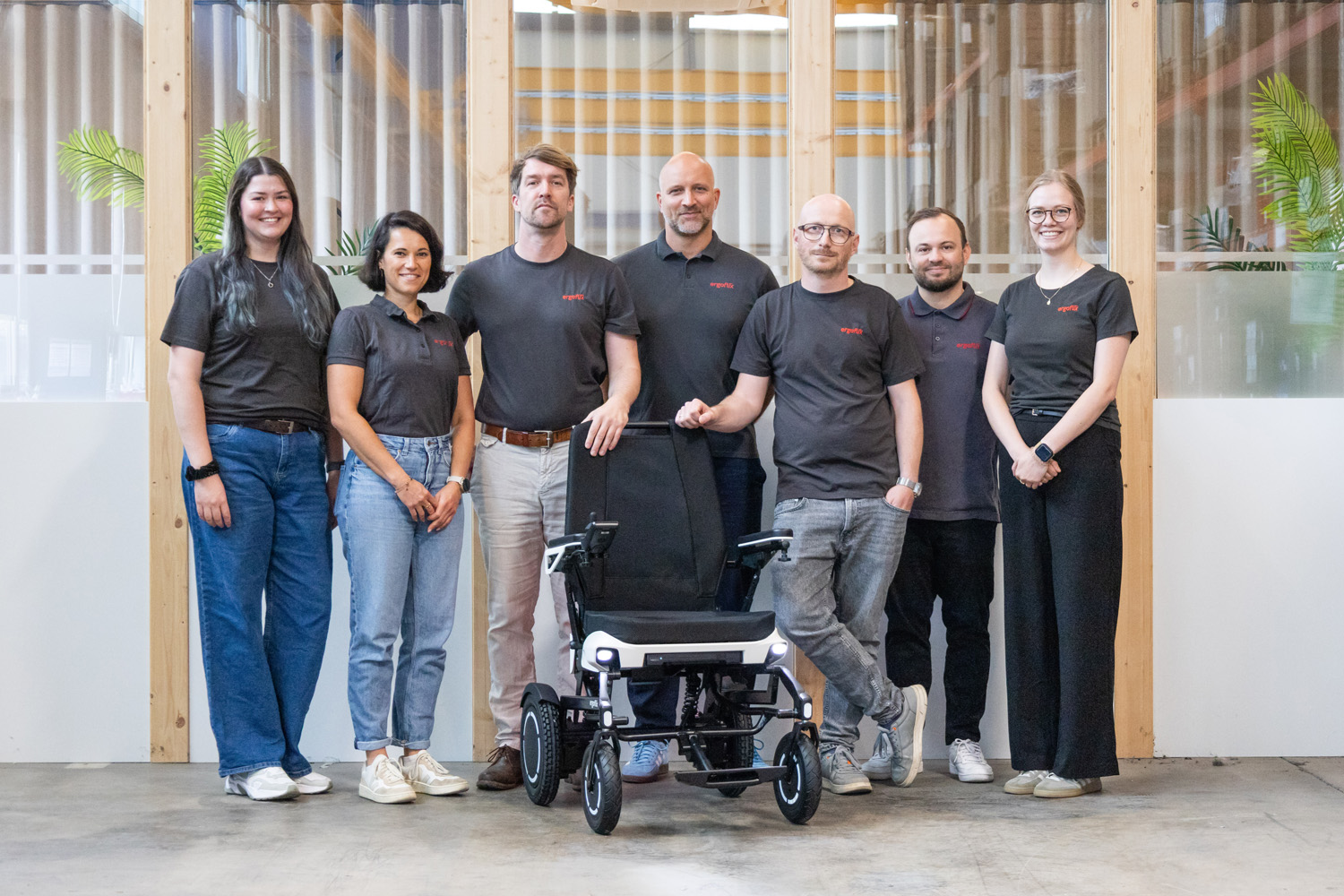 Das Bild zeigt das Produktteam von ergoflix als Gruppe aufgestellt, vor ihnen steht der ergoflix vario.