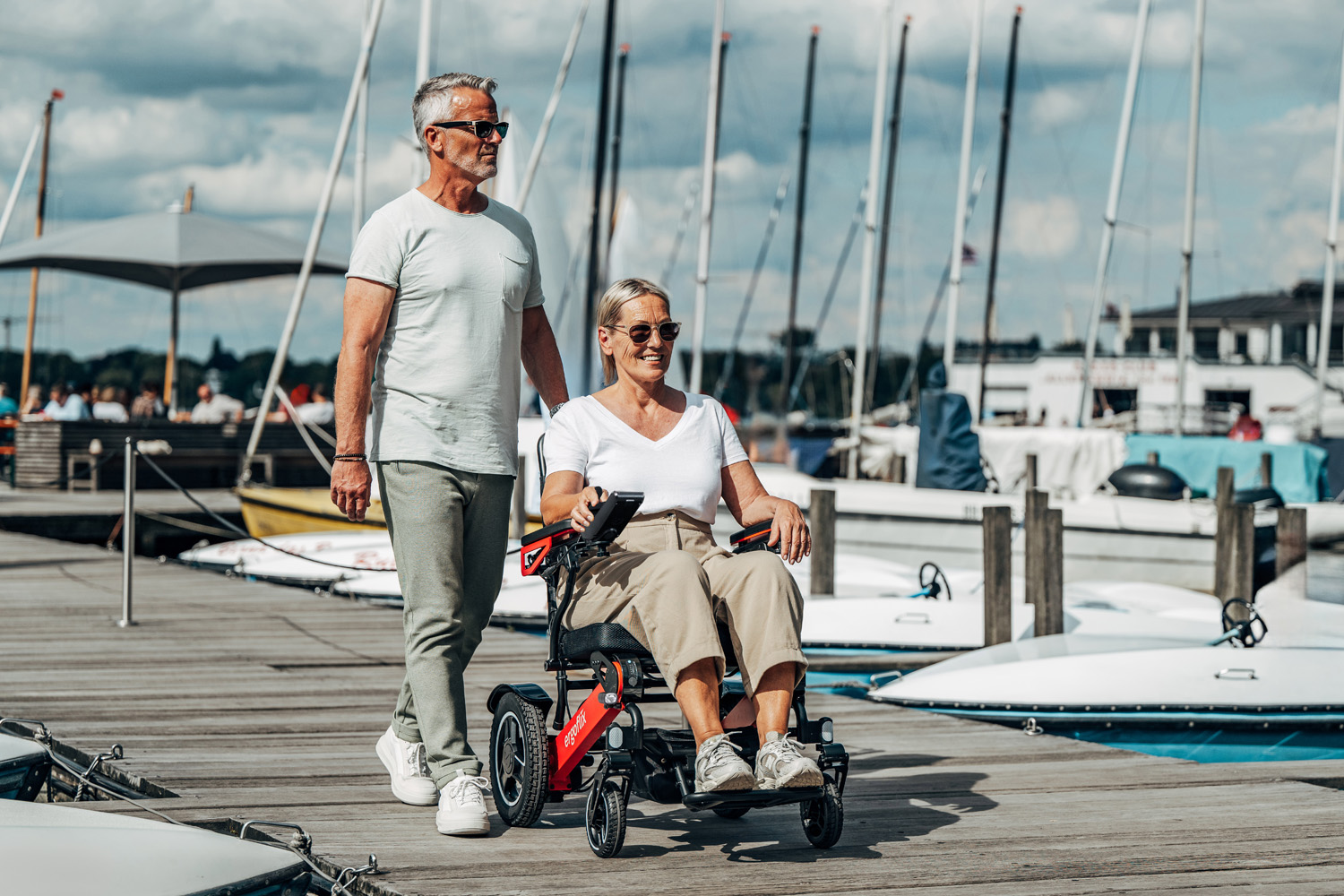 Das Bild zeigt eine Frau in einem ergoflix LX, ein Mann läuft neben ihr und beide befinden sich auf einem Steg am Hafen.