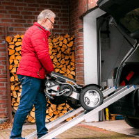 Mann schiebt einen gefalteten ergoflix über eine Rampe ins Auto