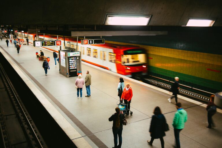 Personen laufen auf einem Bahnstieg während ein Zug einfährt